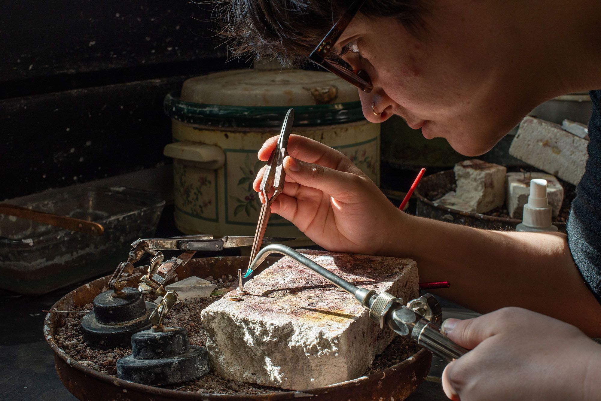 A student welding a small metal piece.