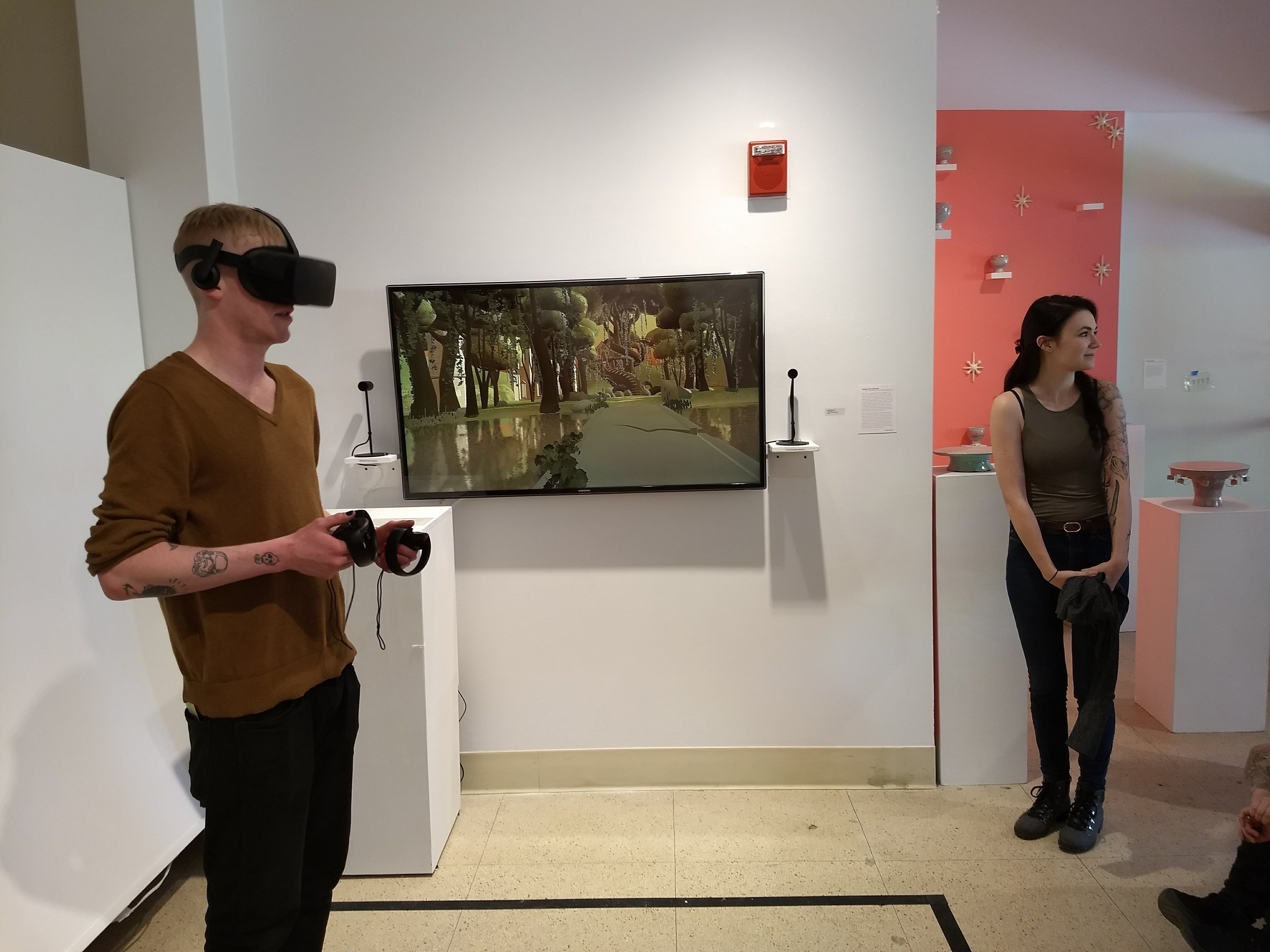 A student wearing a VR headset in front of a screen with a forrest view.