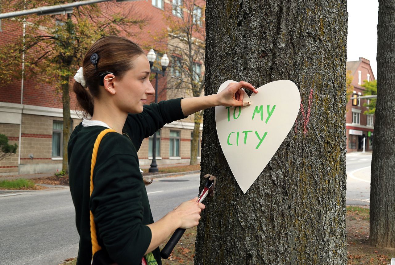 Miia Zellner nailing a heart with the words "To my city" to a tree.