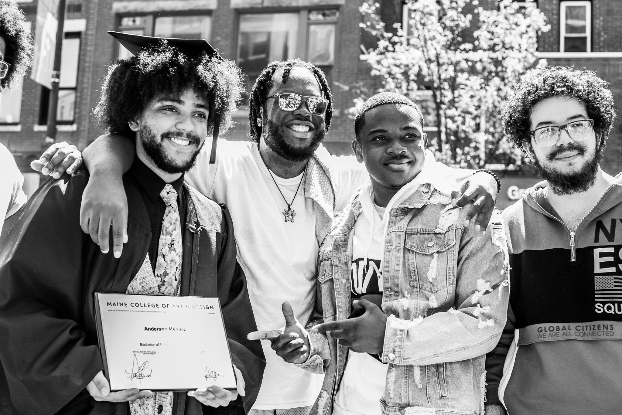 A graduate posing with their family and diploma.