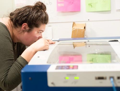 Bethany keeps a close eye on the laser cutter as she cuts pieces for her kinesthetic learning tools.