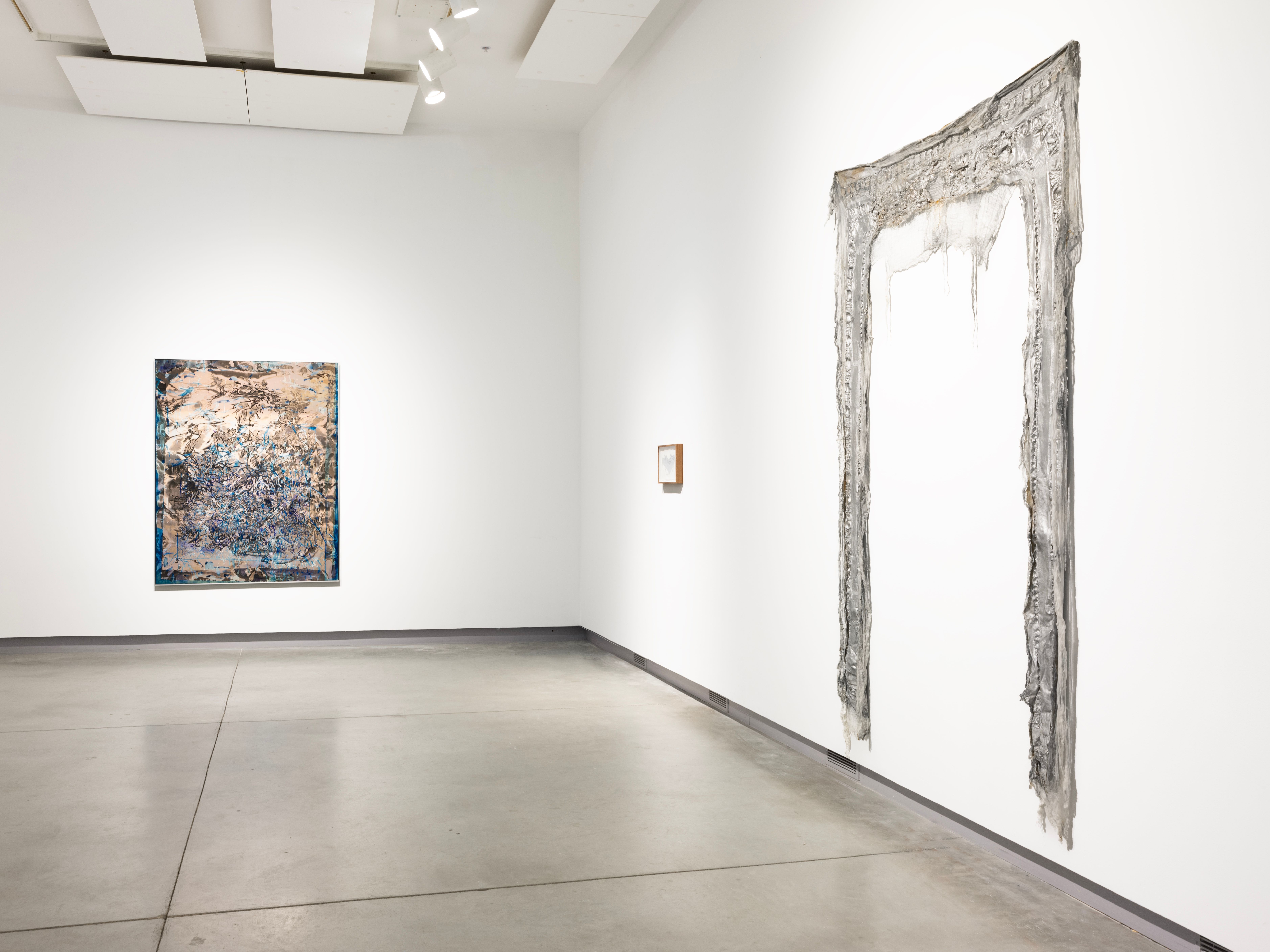 Installation view of ENTER: with three pieces, the left is a large dark painting, the middle is a small piece framed, the right is a metallic fabric hanging sculpture.