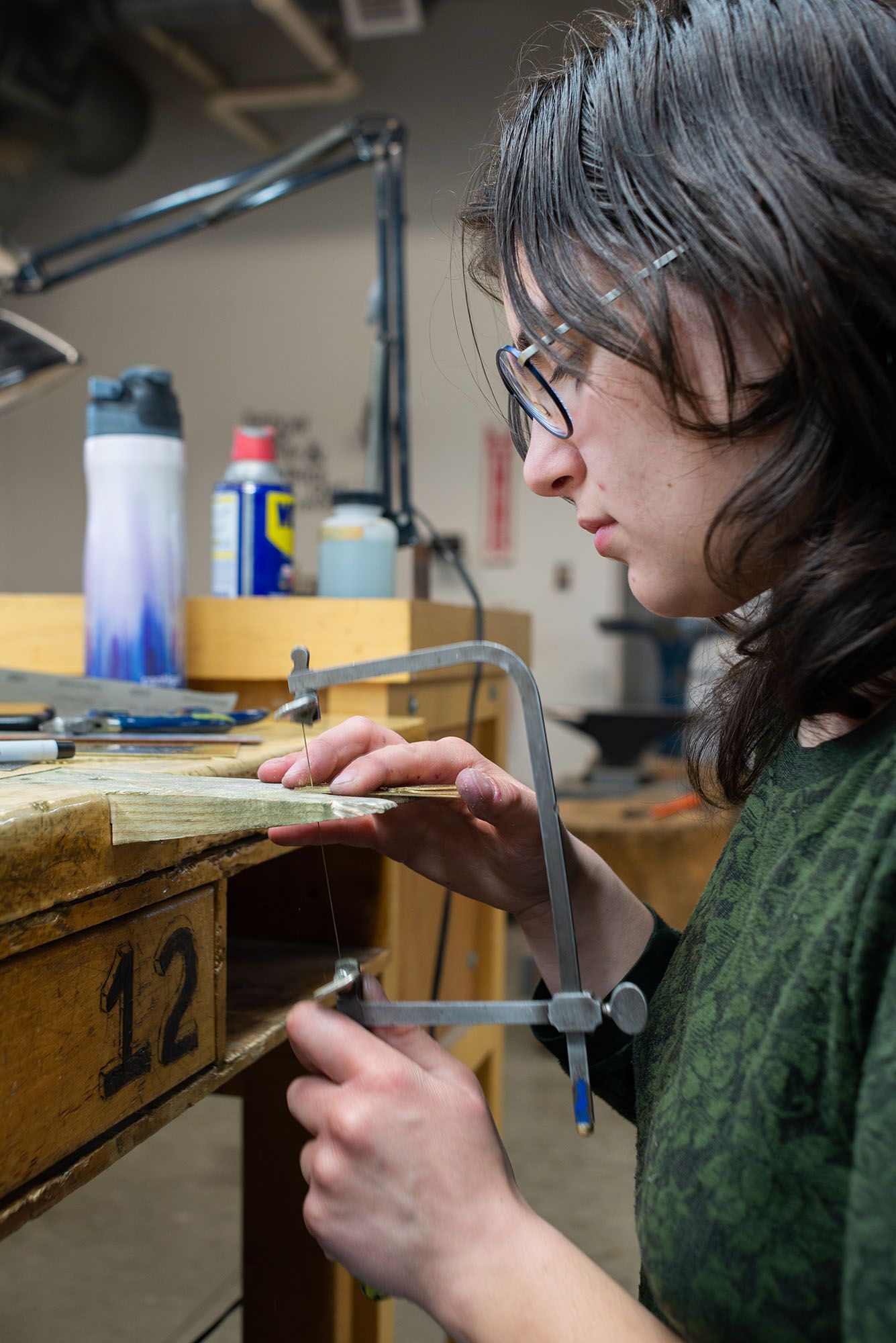 A student sawing a sheet of metal.