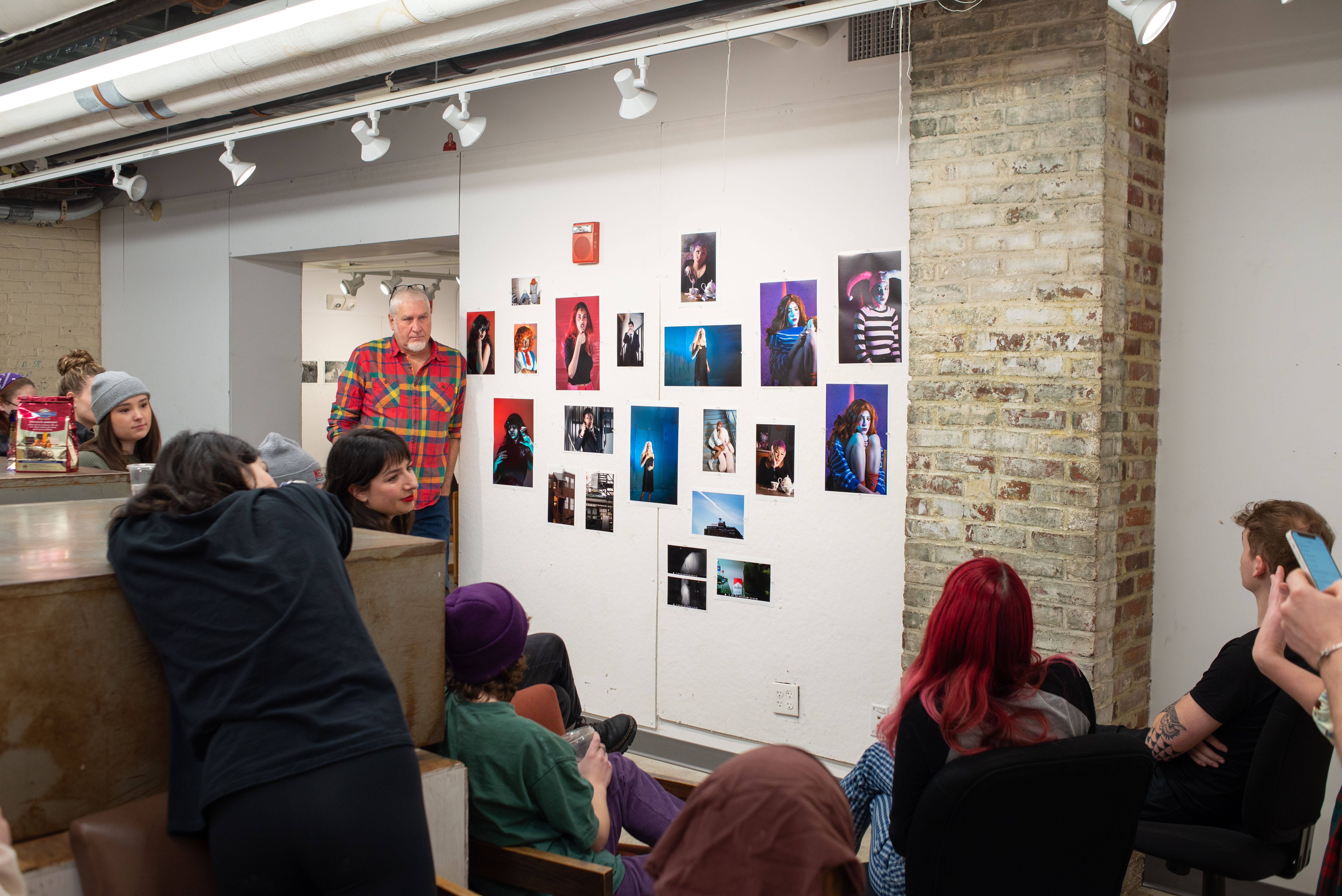 A group of students looking at photography work on a wall during a critique.