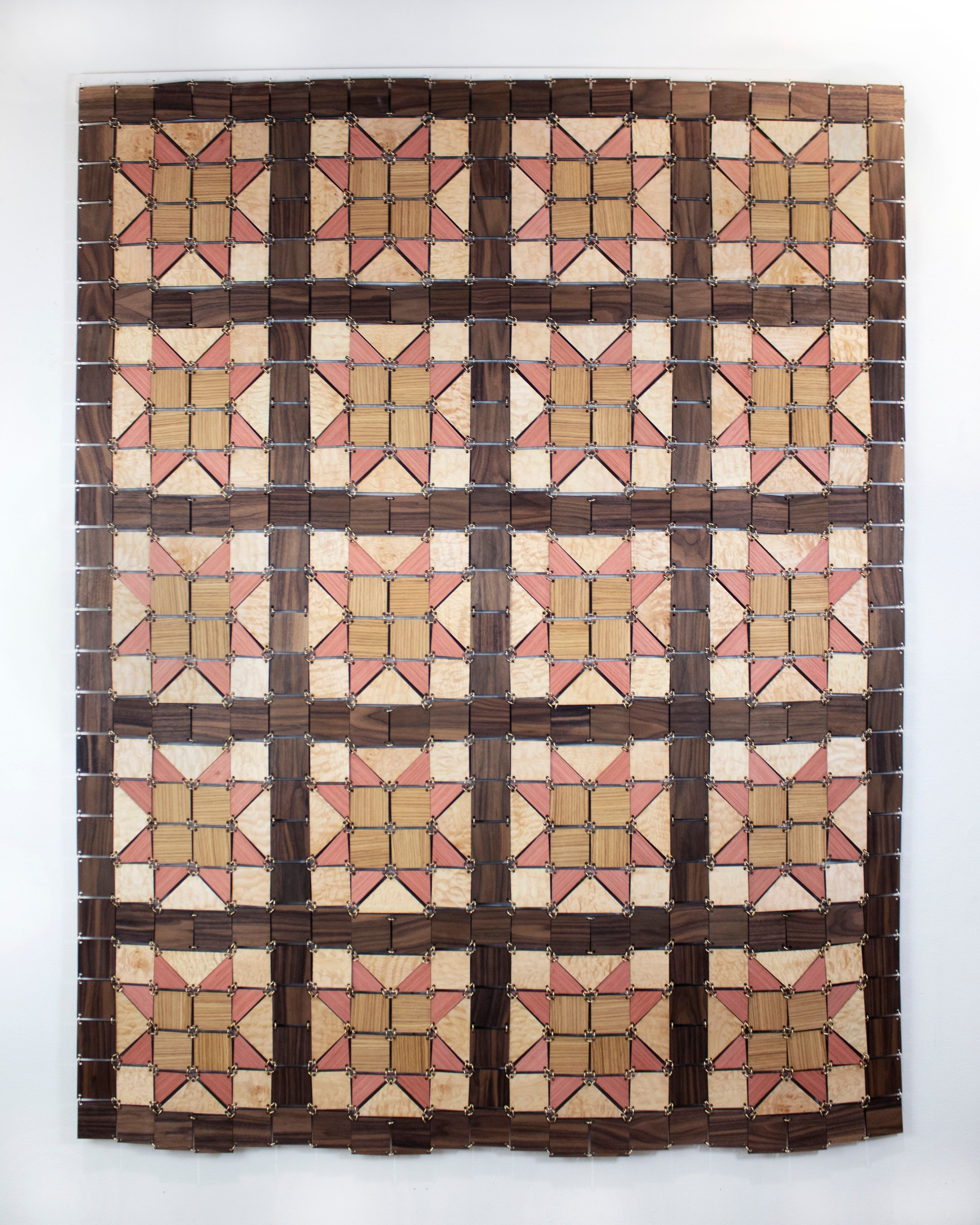 A quilt made from blocks of wood connected with brass jump rings.
