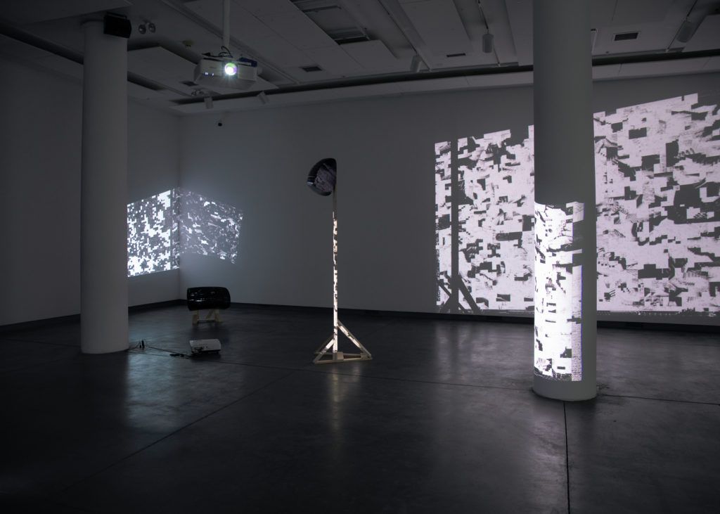 Gallery view of two distorted projections and two sculptural objects.