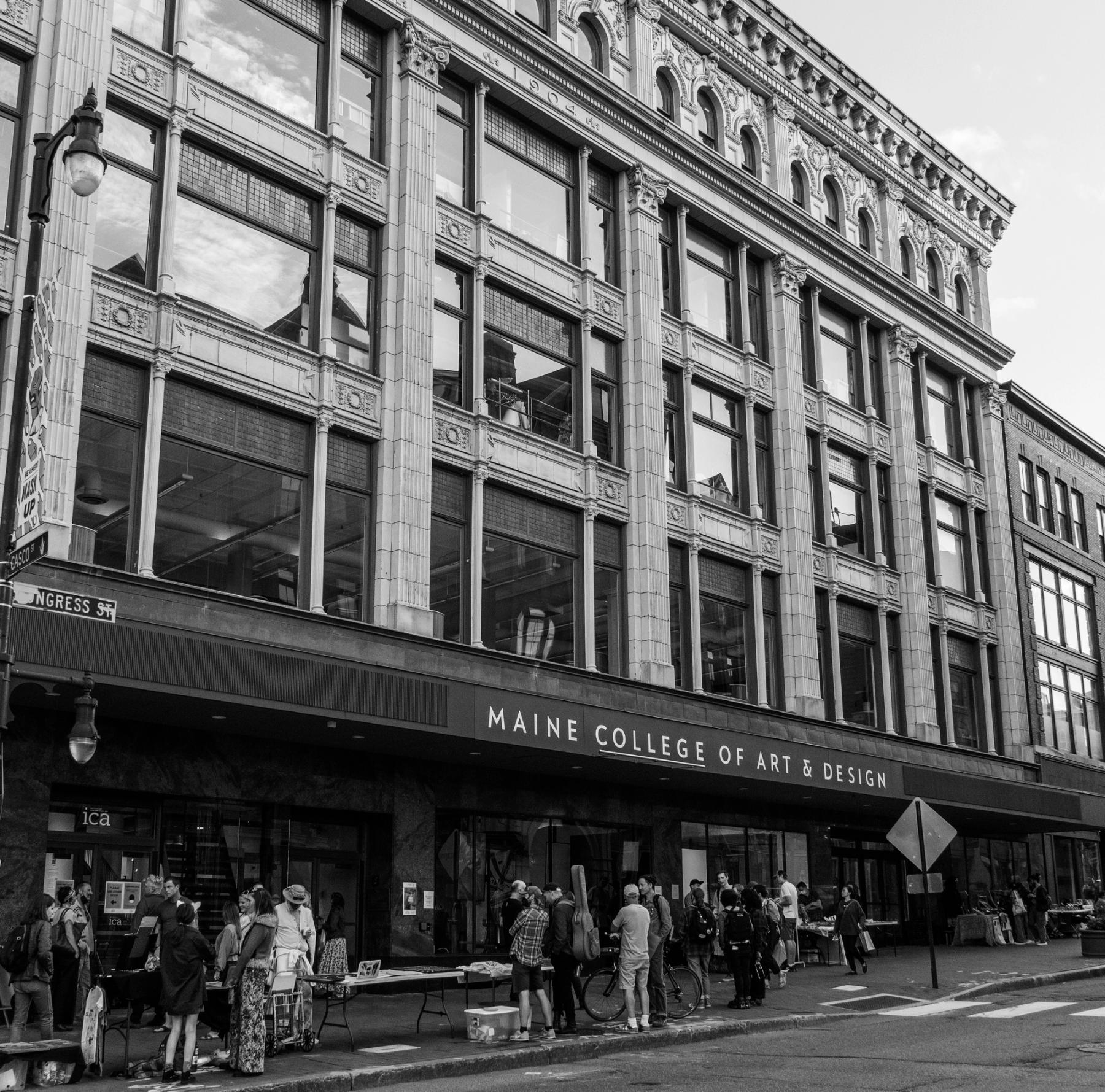 Black and white, bustling, outside view of the Porteous Building during a First Friday Art Walk.