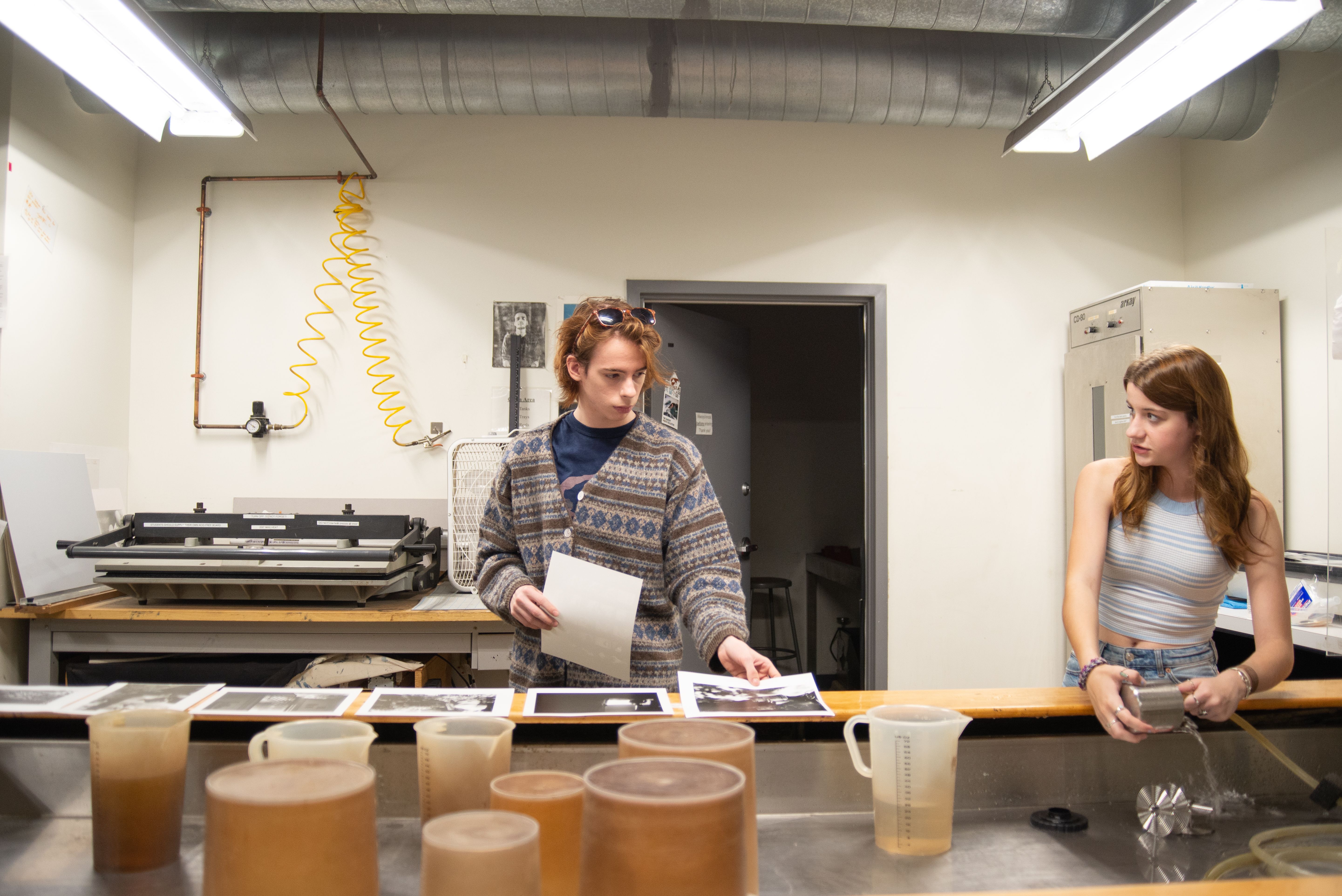 Two pre-college students working on developing photographs.