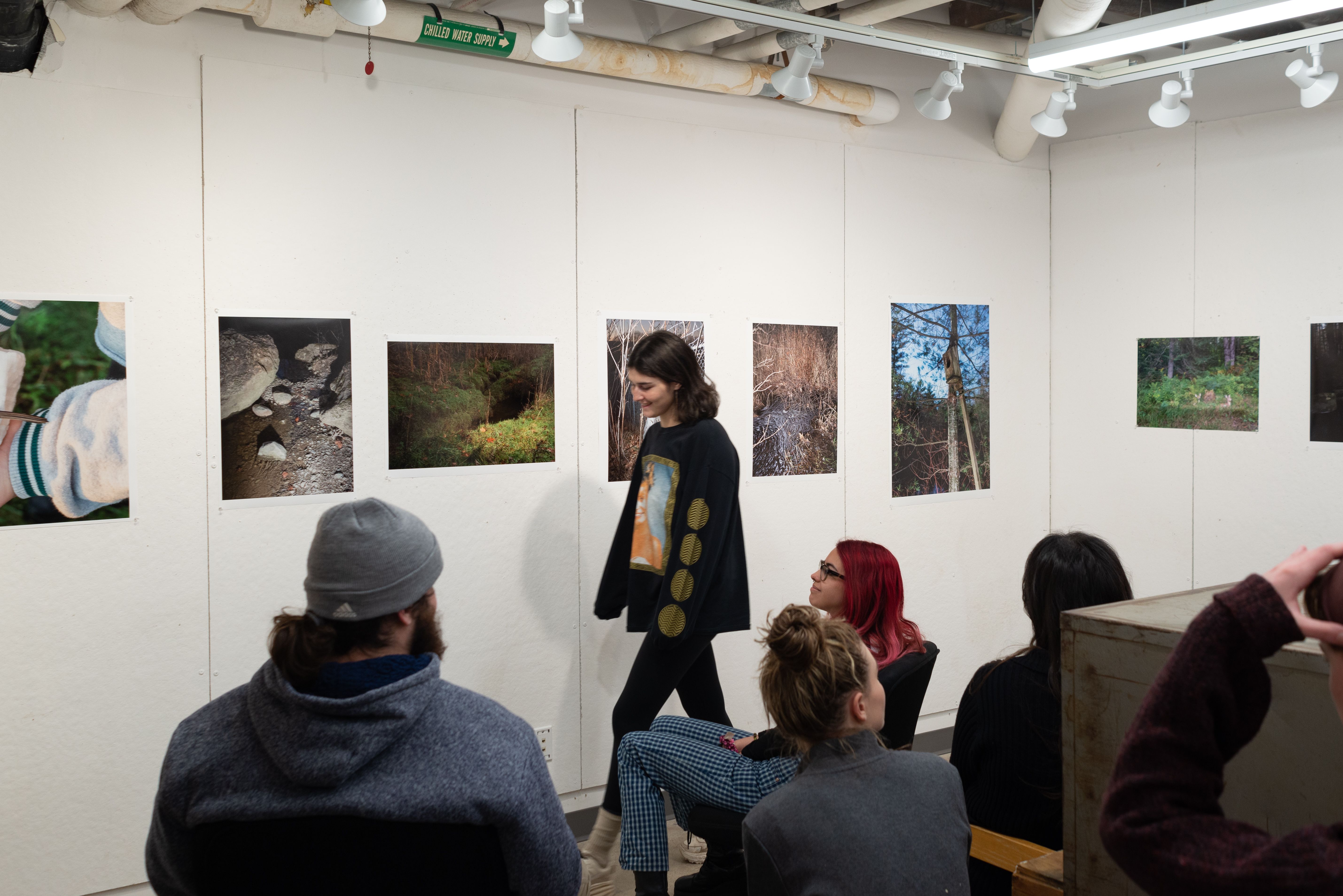 A group of students critiquing photographs on the wall.