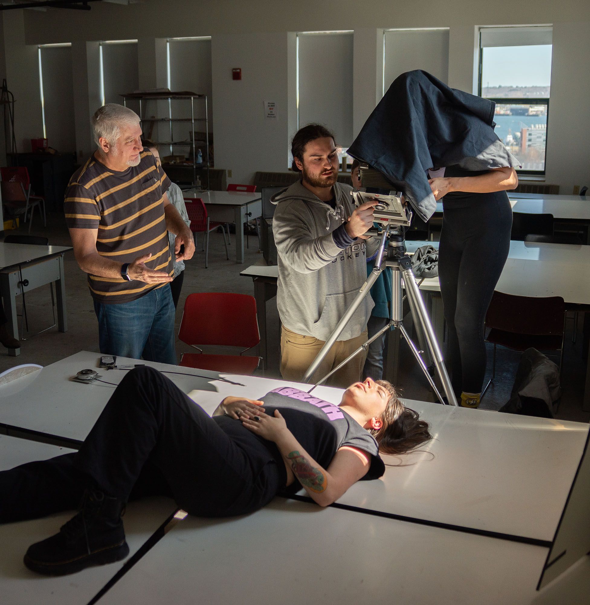 Students taking a photograph of someone laying on a table.