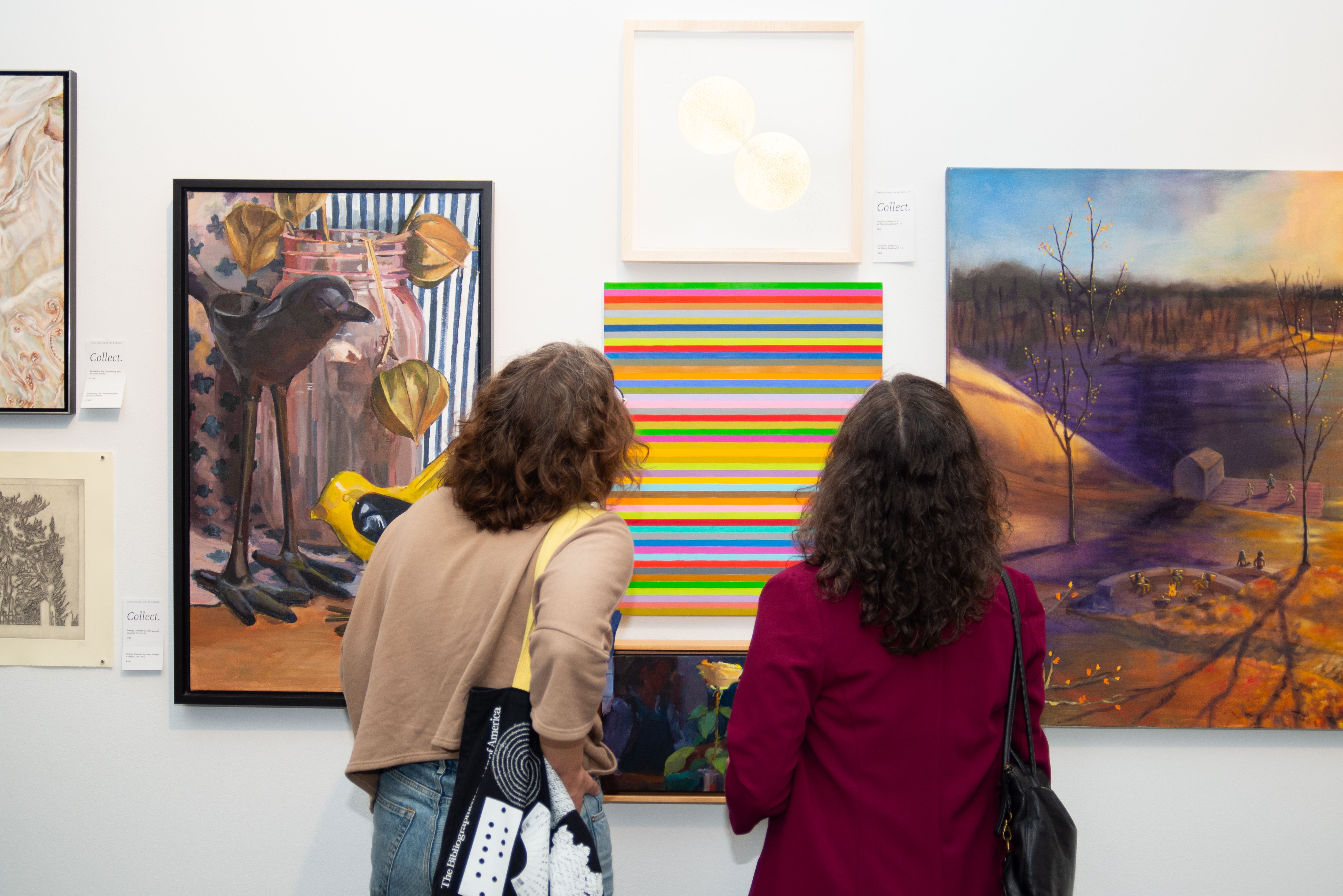 Two people looking at a striped painting.