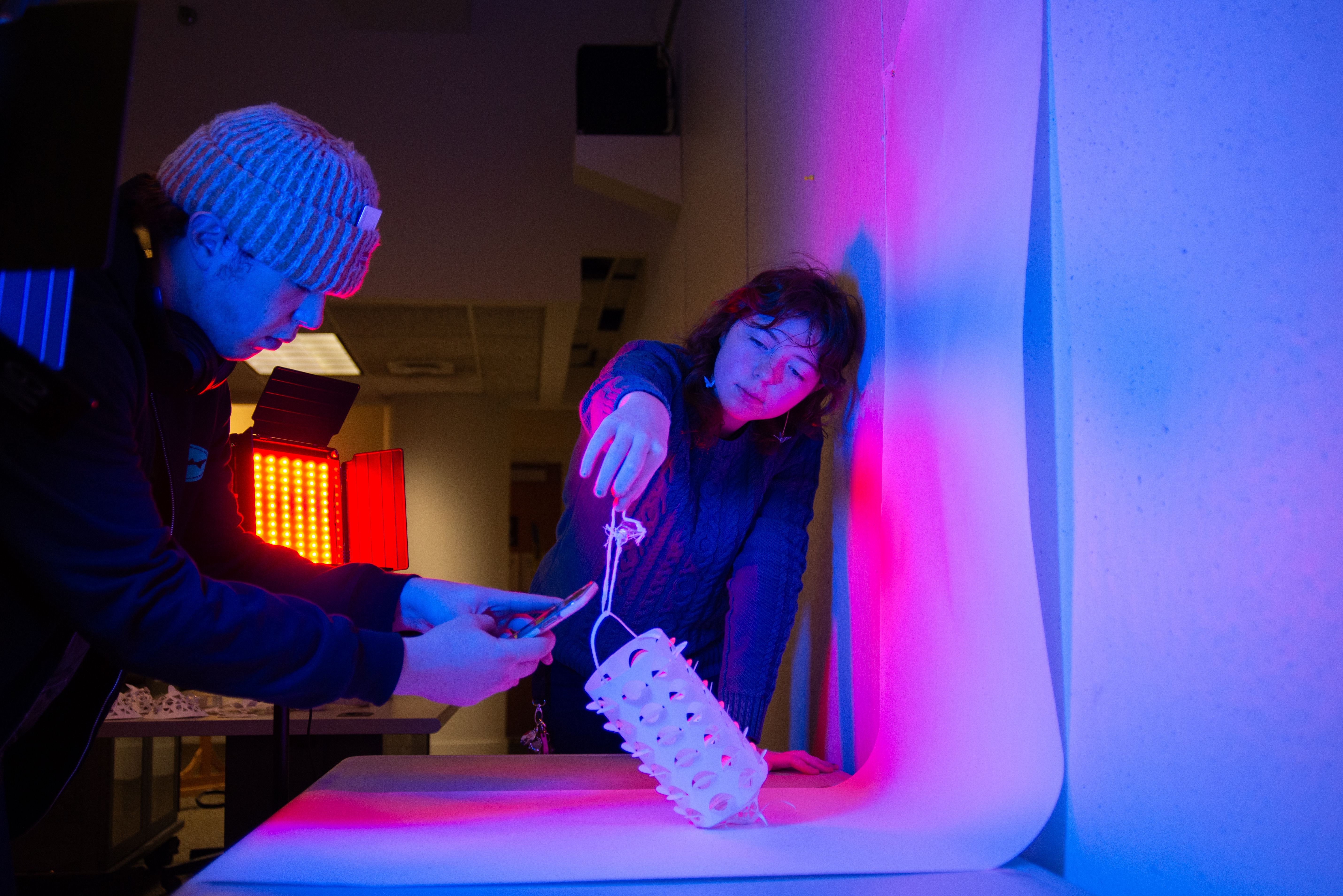 Students photographing a paper sculpture in red and blue lights