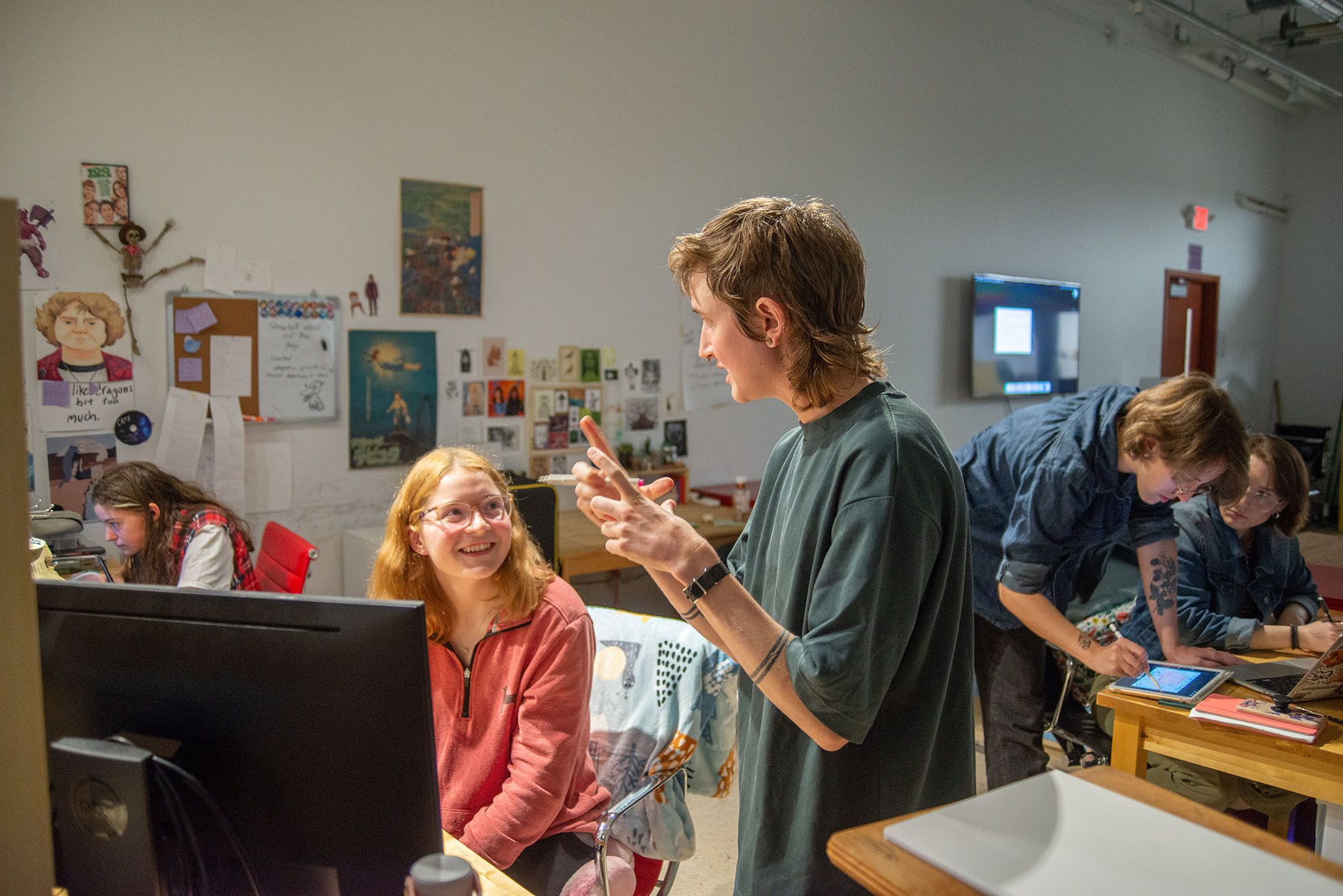 A visiting artist speaking with a student in the Animation & Game Art studio space.