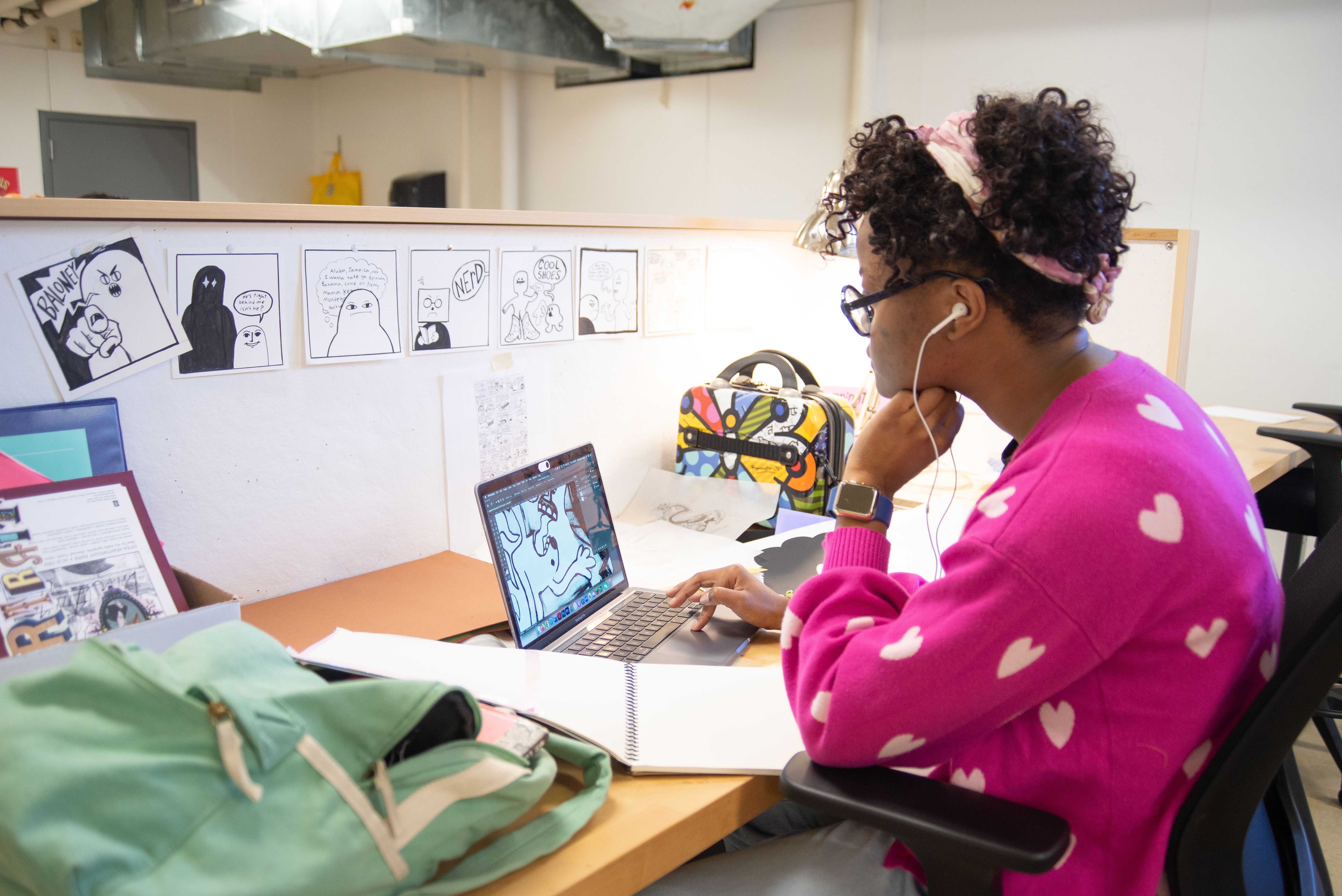 View of an illustration studio space with a student working on their laptop.