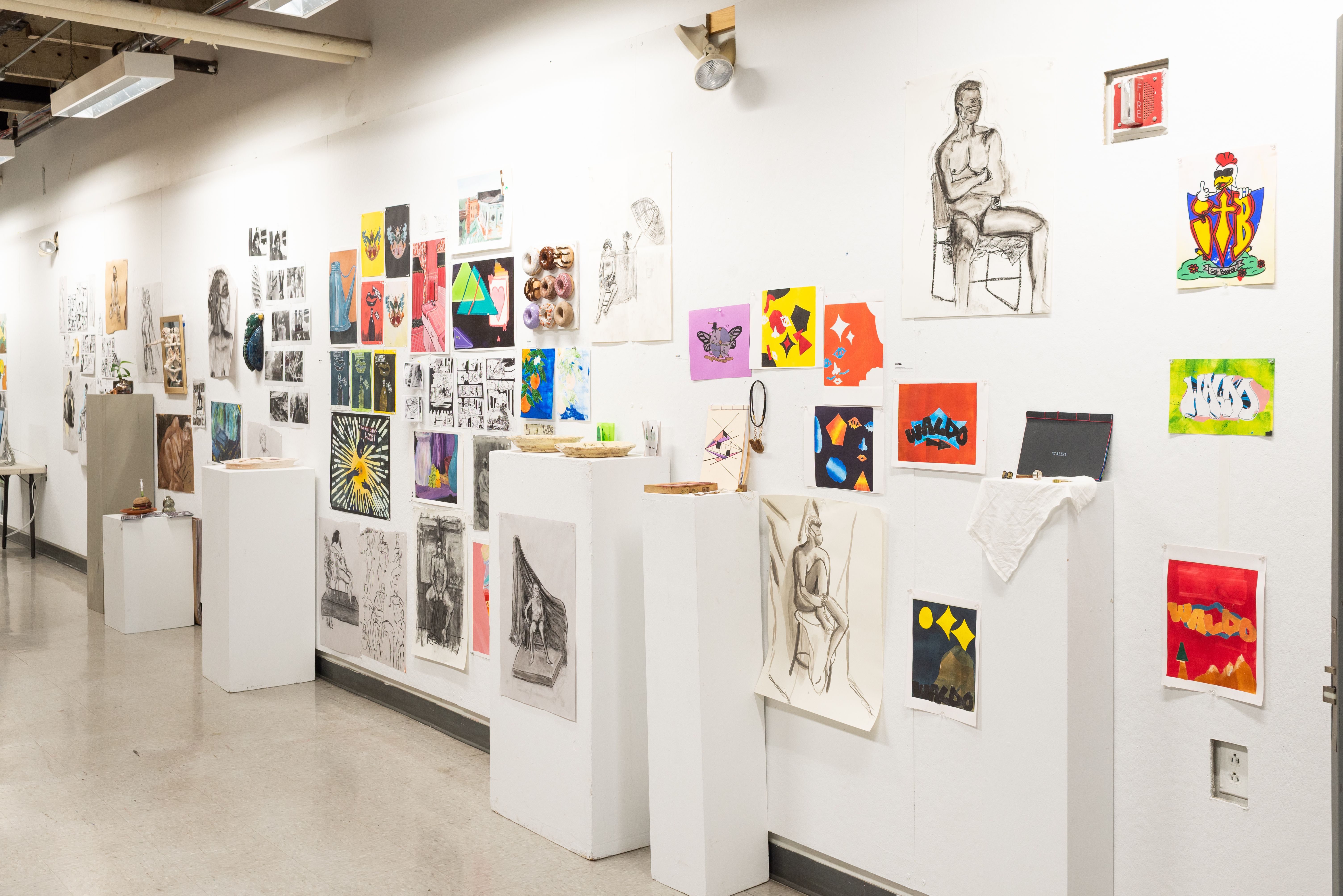 View of installed work by Pre-College students, charcoal drawings, prints, photography, and ceramics.