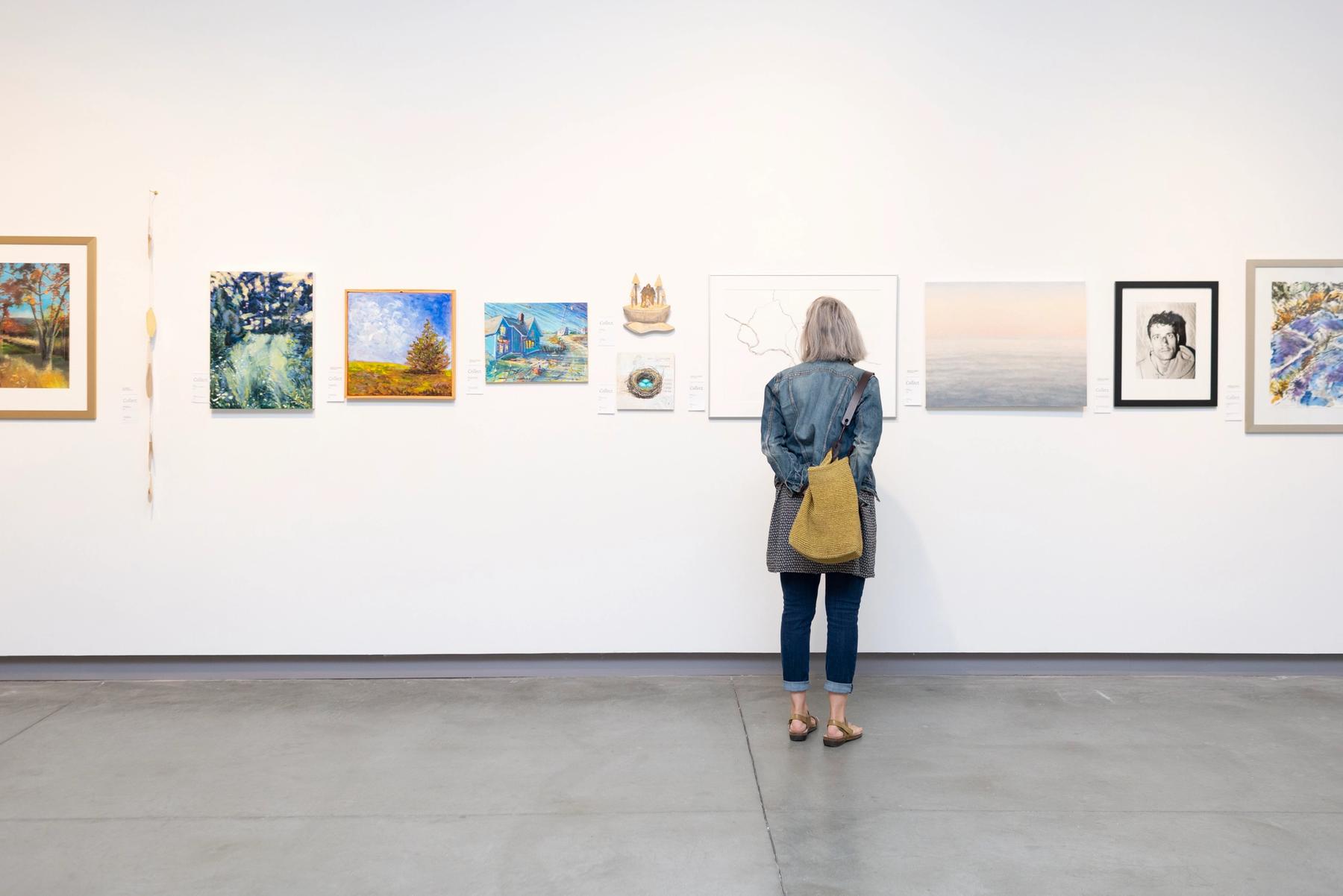 A person looking at a collection of a variety of art.