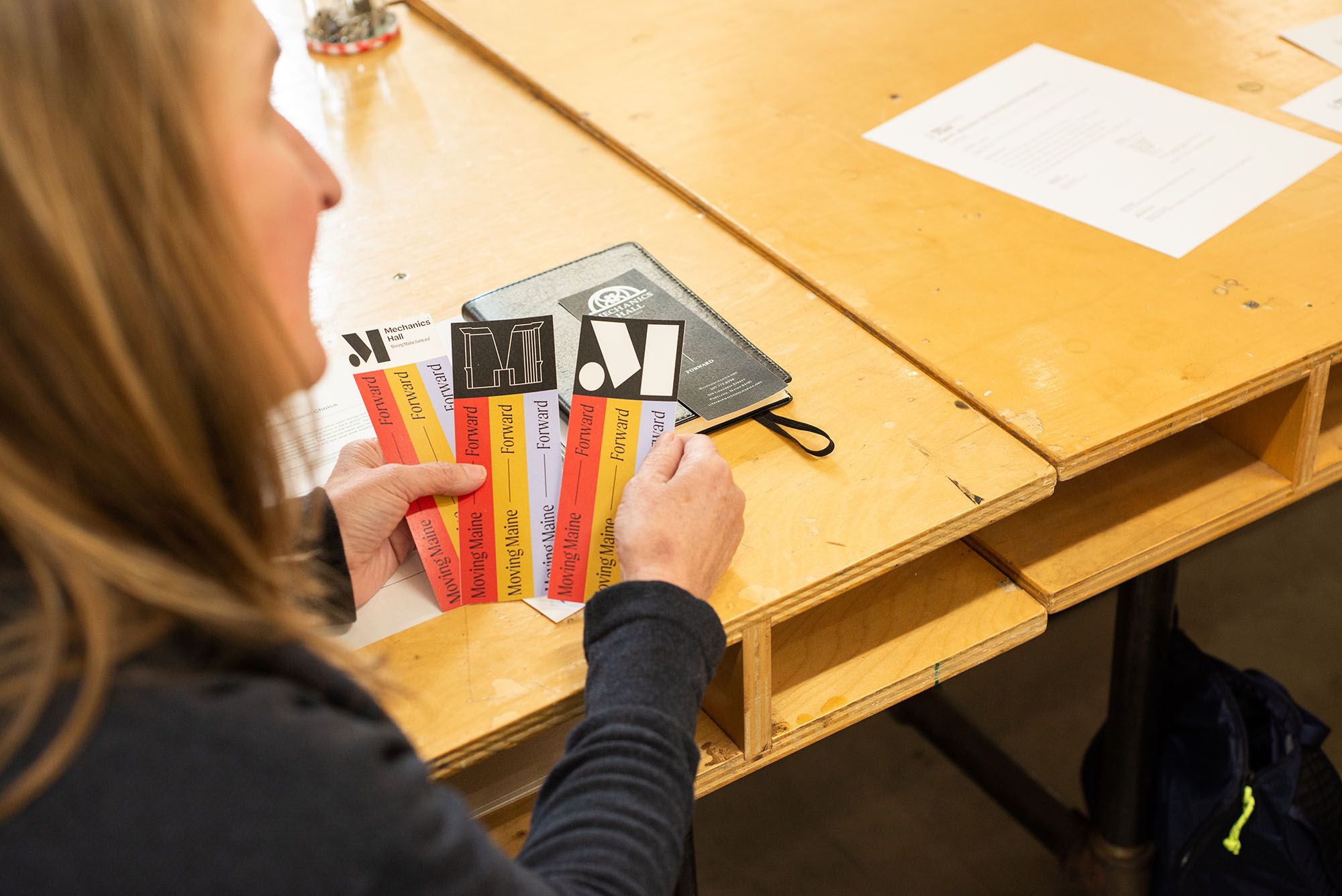 A community member looking at three logo options for a Mechanics' Hall rebrand.