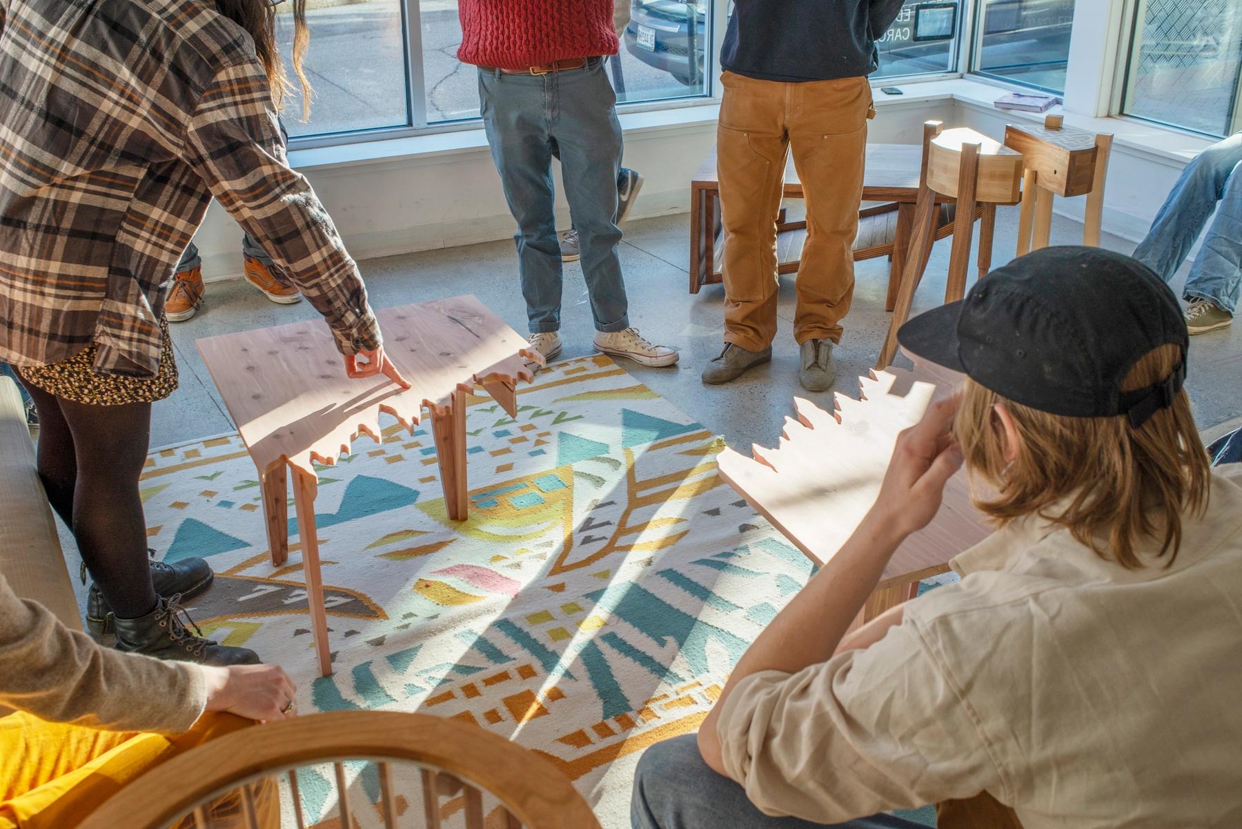 Student pointing towards a sculptural wooden table