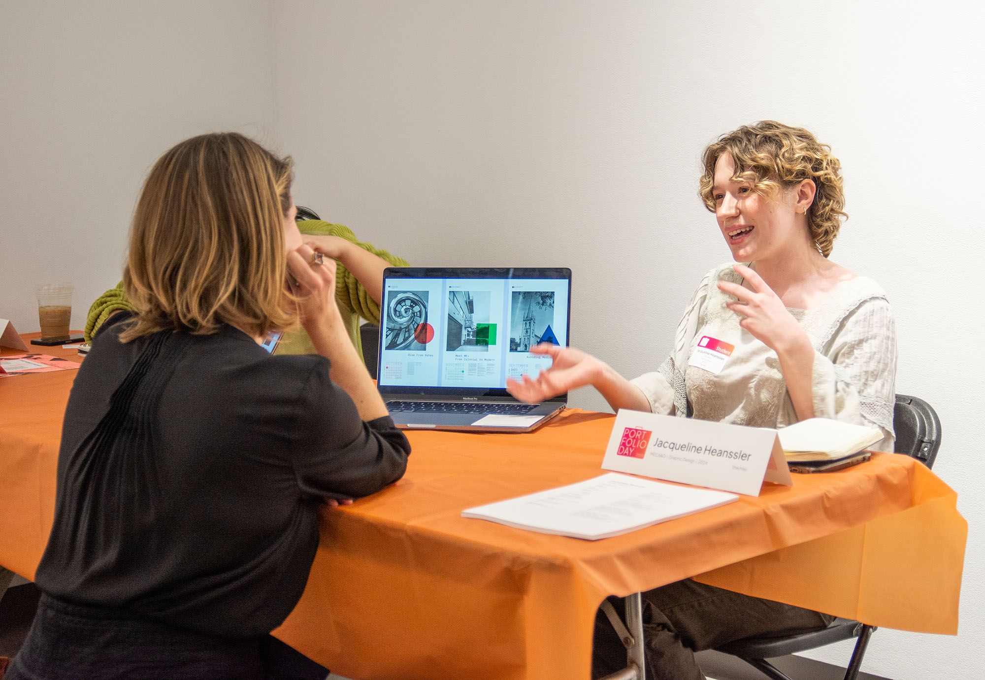 Student presenting three poster designs on their laptop during a Portfolio Day.