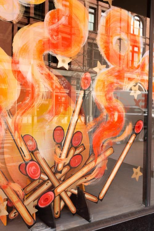 A window painting of a fire with matches and stars.