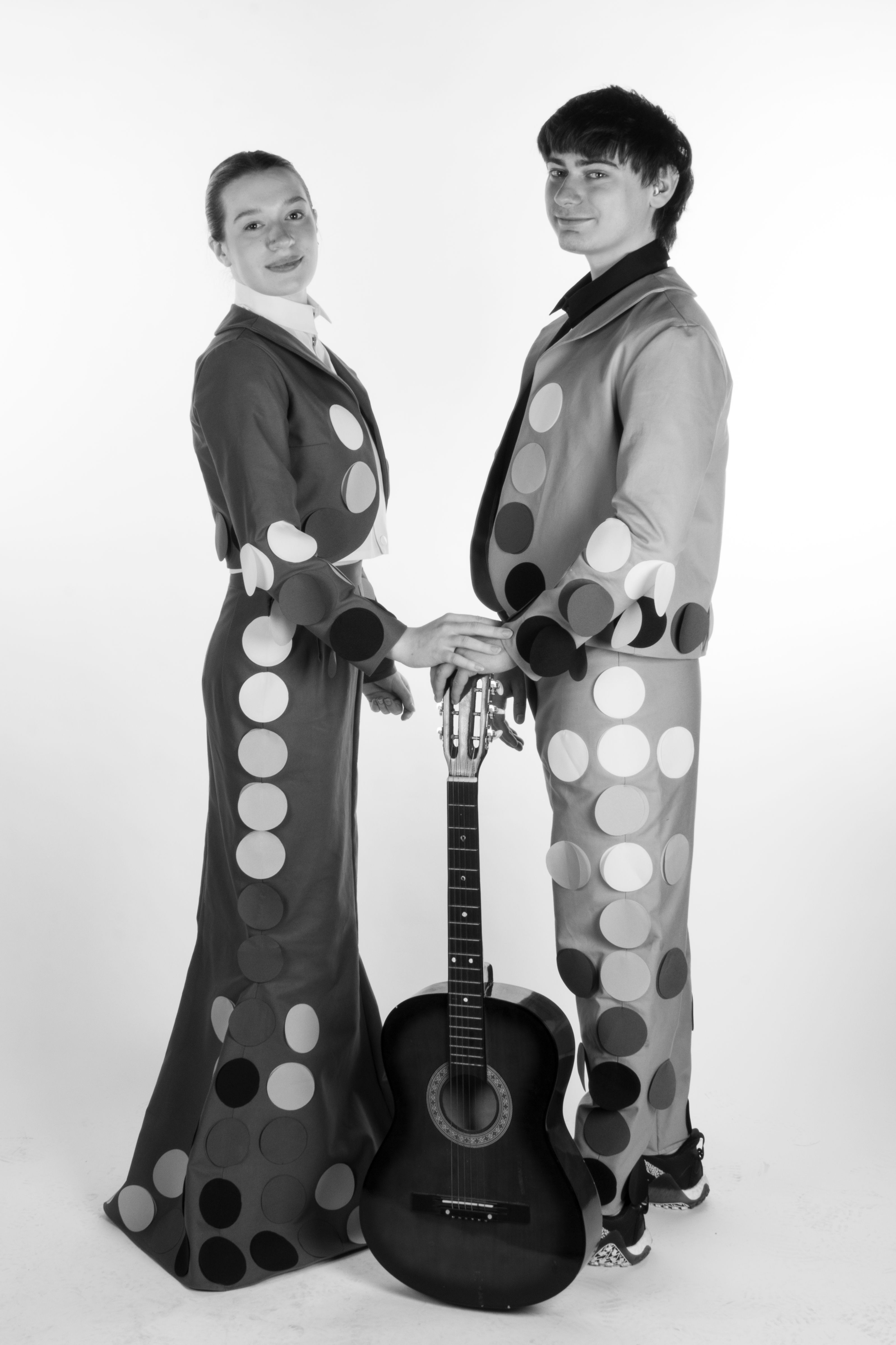 Two models wearing black and white mariachi inspired outfits with large circle details.