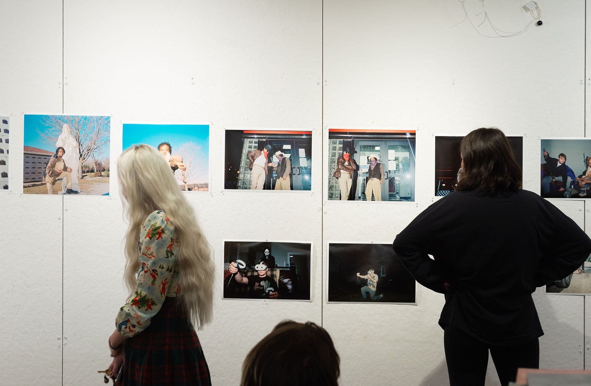 Students looking photographs pinned to a wall during a critique.