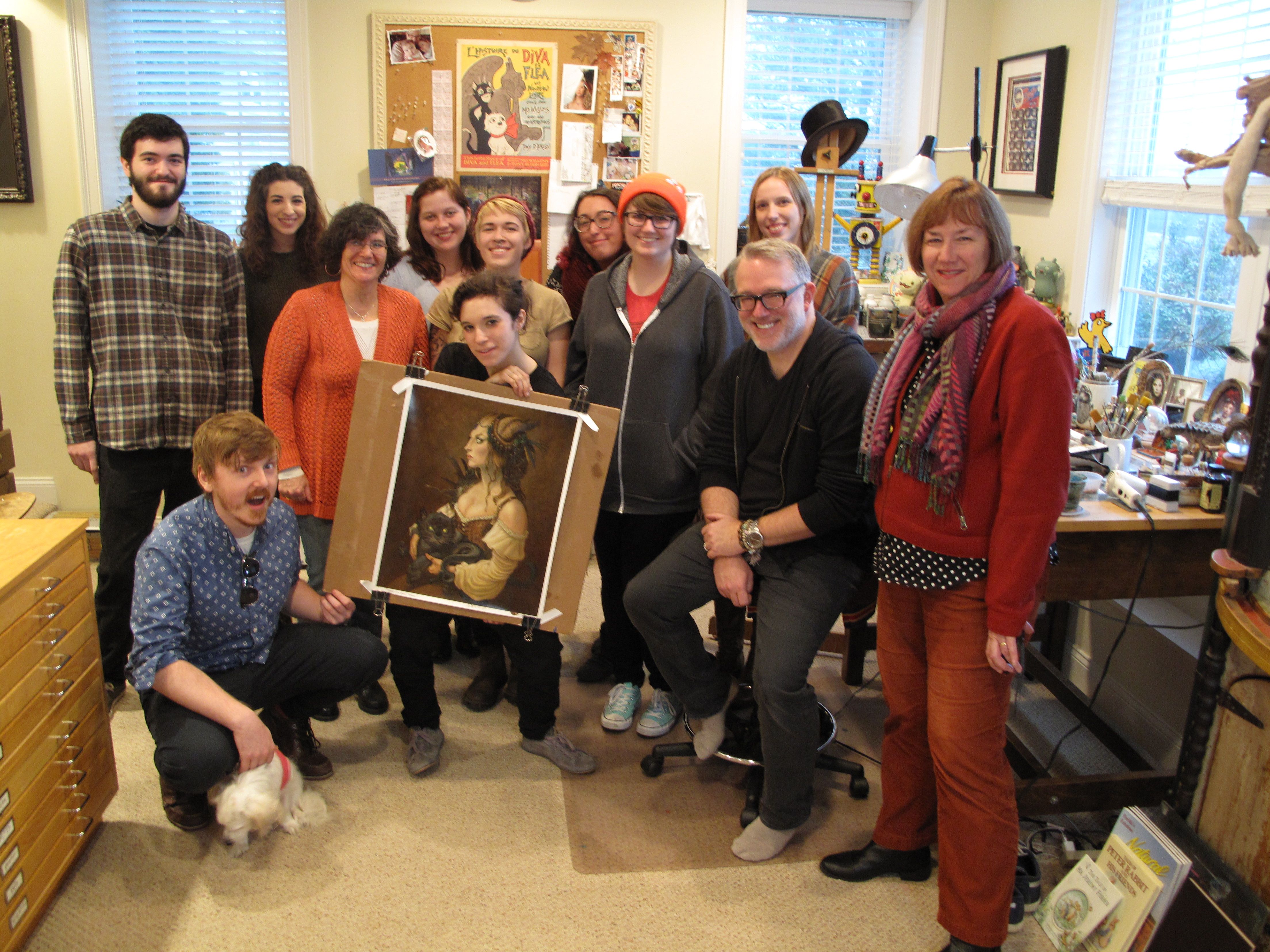 A group of students and professors posing with an illustration during a studio visit.