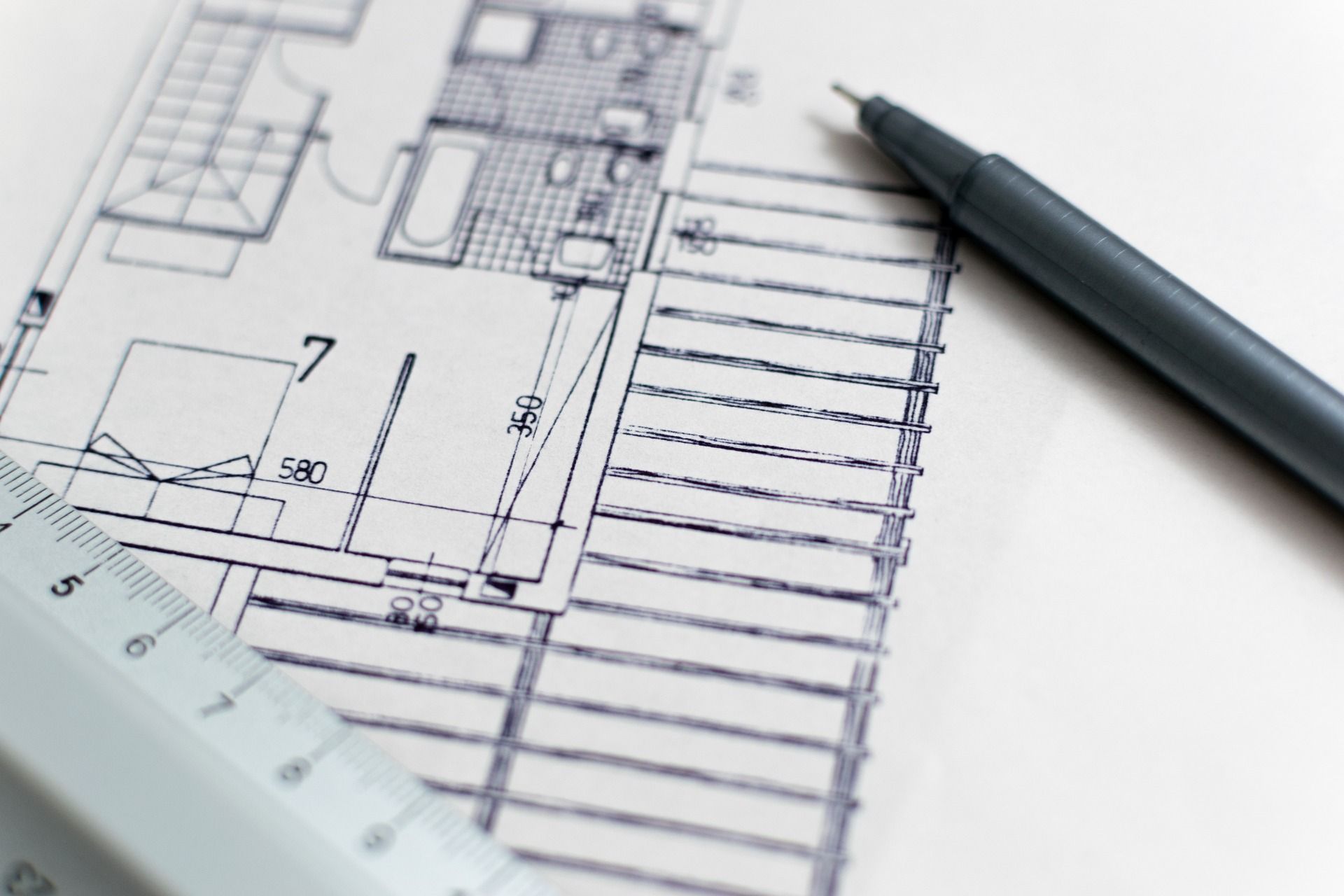 A floorplan and a drafting pencil, illustrating new construction planning.
