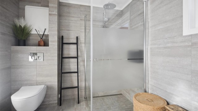 Flislagte overflater, behagelig gulvvarme og stilren servantinnredning med speil og sidelys. Badet har også vegghengt toalett og et elegant dusjhjørne med både hånddusj og regndusj.