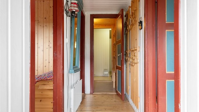 En gang med heltre gulv og fargerike dører leder inn til to av soverommene