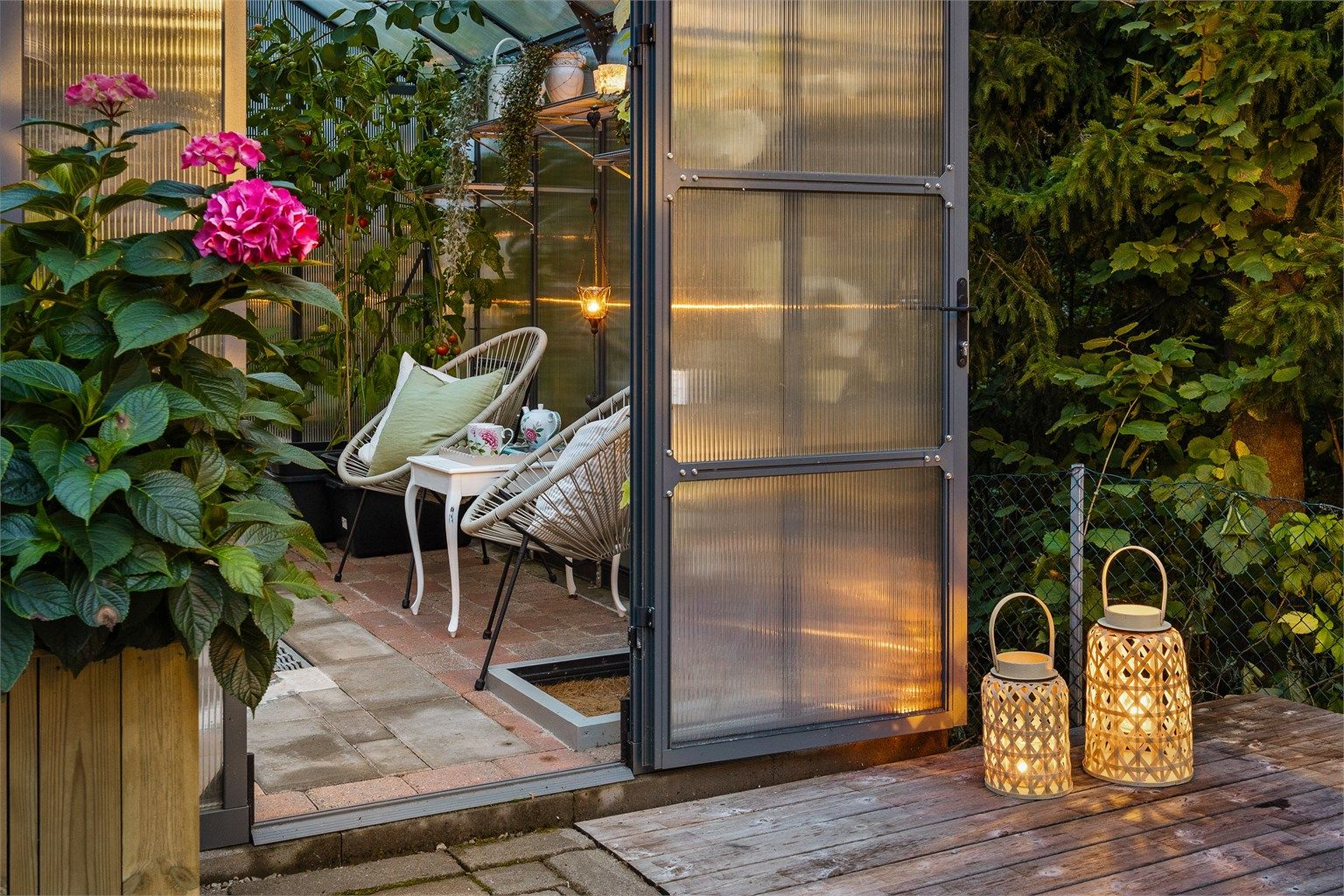 Tilgang til et frittstående drivhus på 9 kvm med belegningsstein på gulv og innlagt strøm/strømuttak, mellom boligen og garasjen.