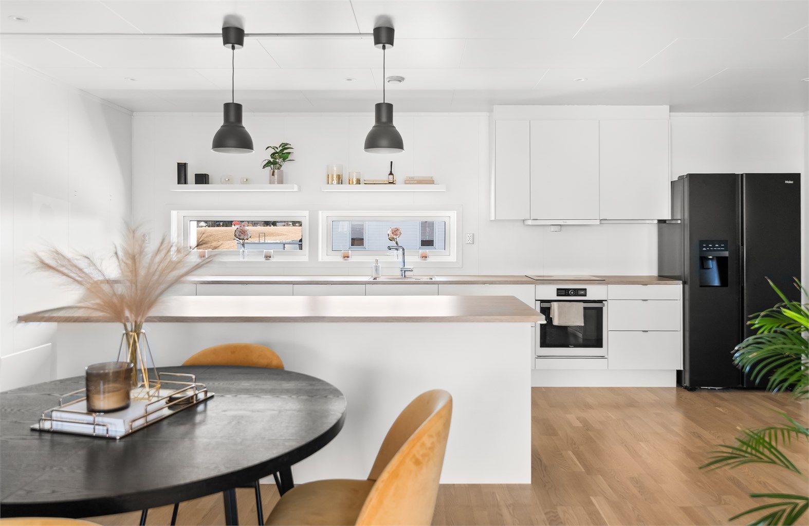 Kjøkkeninnredning fra Sigdal med hvite, glatte fronter, laminatbenkeplate og integrert komfyr og oppvaskmaskin.