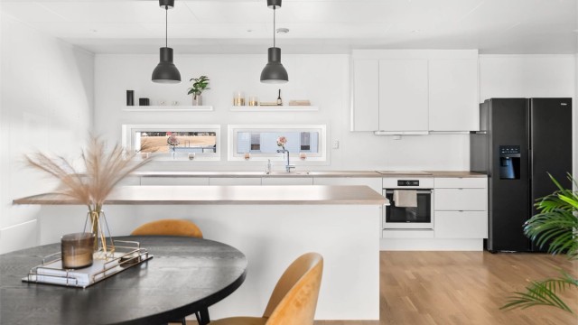 Kjøkkeninnredning fra Sigdal med hvite, glatte fronter, laminatbenkeplate og integrert komfyr og oppvaskmaskin.