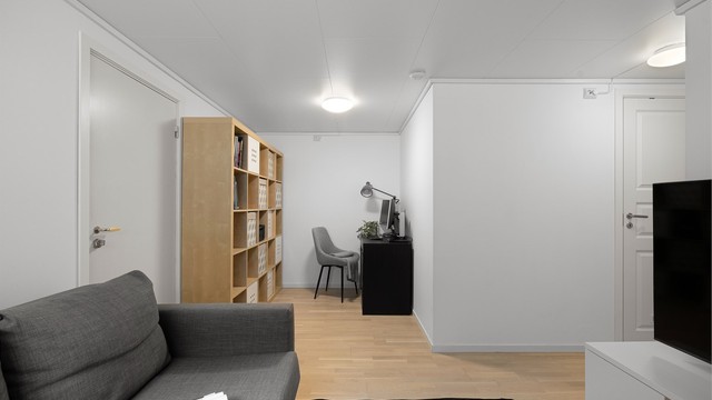 Kjellerstue med plass til både sofa, tv og en kontorplass.