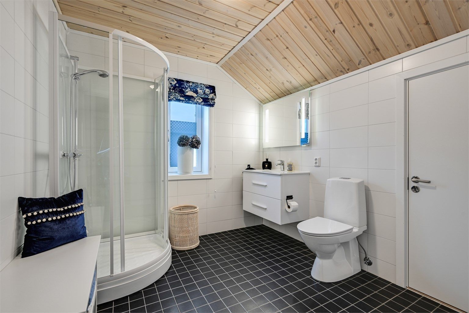 Et flislagt bad med varmekabler i gulv, innredet med heldekkende servant, gulvmontert toalett og dusjkabinett.