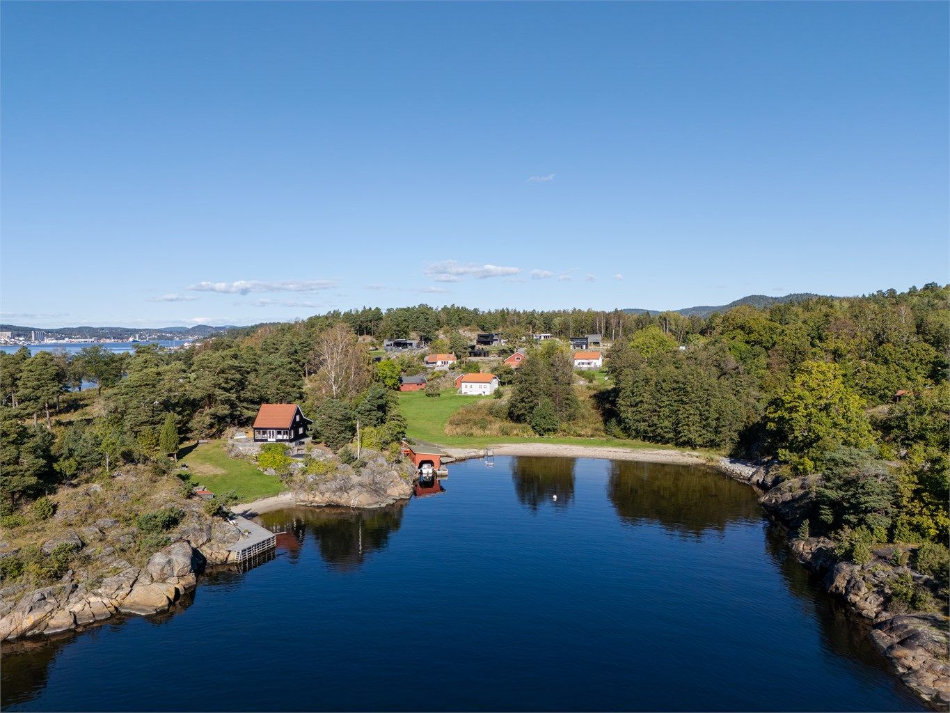 En idyllisk vik med sandstrand og båthus i nærområdet.