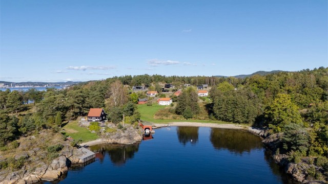 En idyllisk vik med sandstrand og båthus i nærområdet.