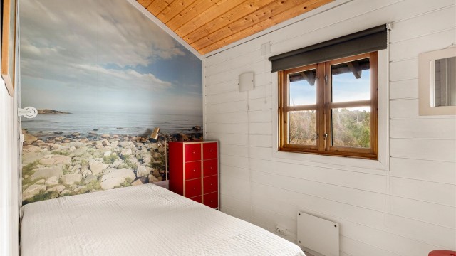Alle rom har sin egen stemning som springer ut av møblene og tingene i det, og påvirkes av tid, sted og menneskene som bruker det. Dette soverommet har fått spesiallaget en fondvegg med kulesteinene på Jomfruland. Den kjente øya kan sees fra vinduet her.