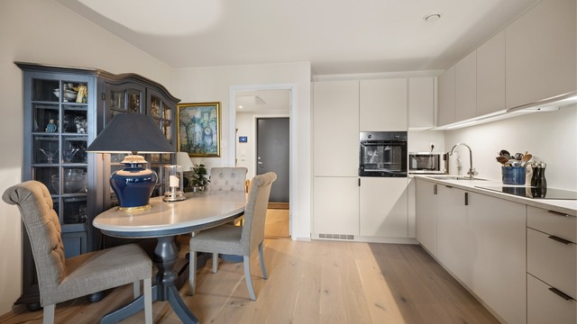 Pent og moderne kjøkken med slette fronter, integrerte hvitevarer og god plass til spisebord.