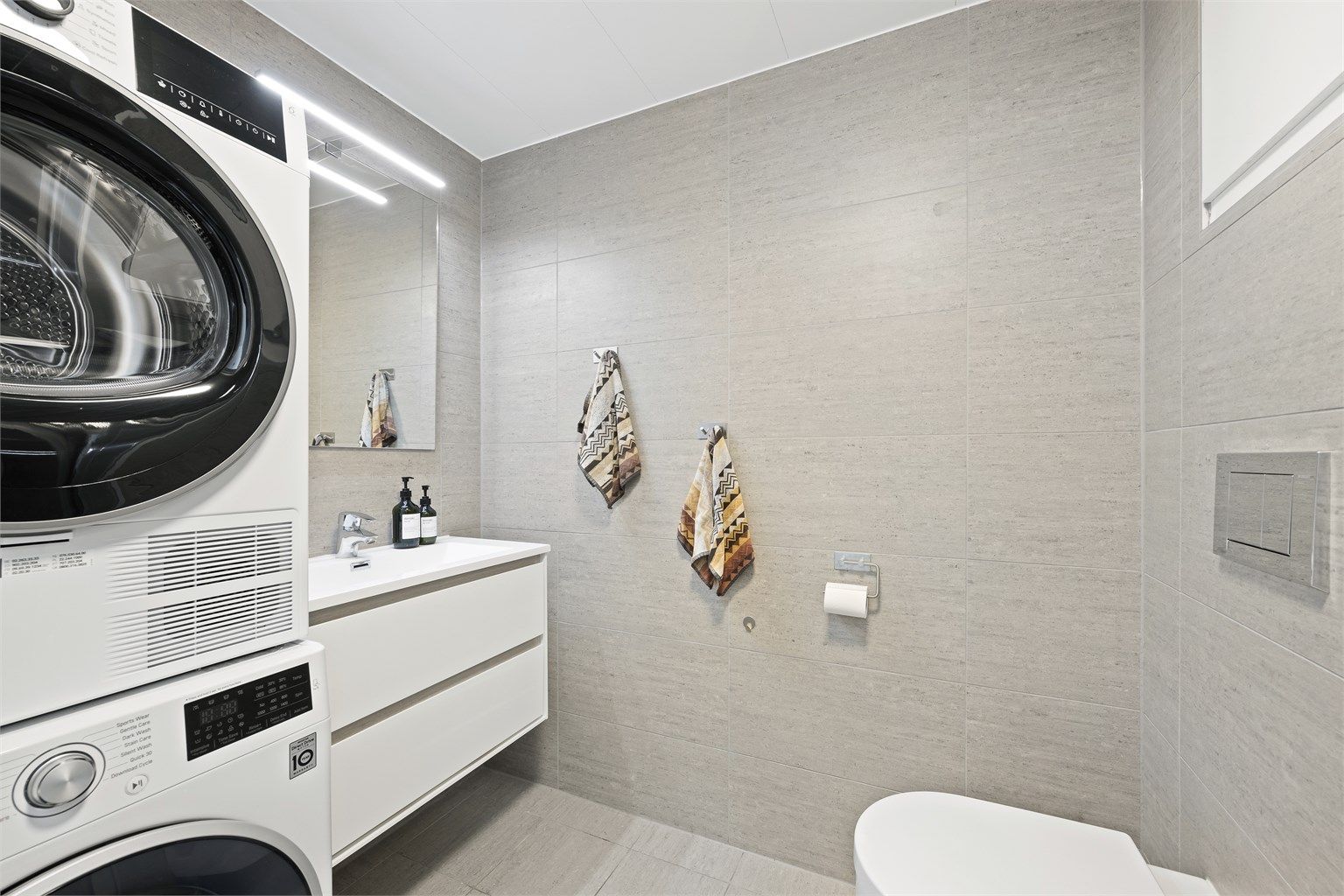 Lekkert og flislagt bad med gulvvarme. Plass og opplegg til vaskemaskin og tørketrommel. Badet er fra byggeår. Det ble i 2018 lagt flis på flis, samt ny servant, armatur og dusjarmatur  