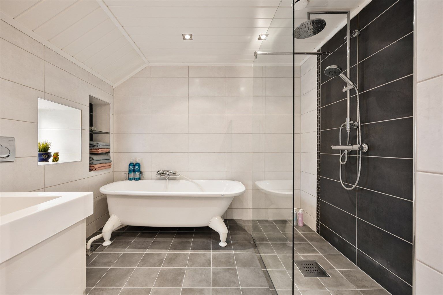 Her er det både et frittstående badekar og en separat dusjsone med glassvegg.