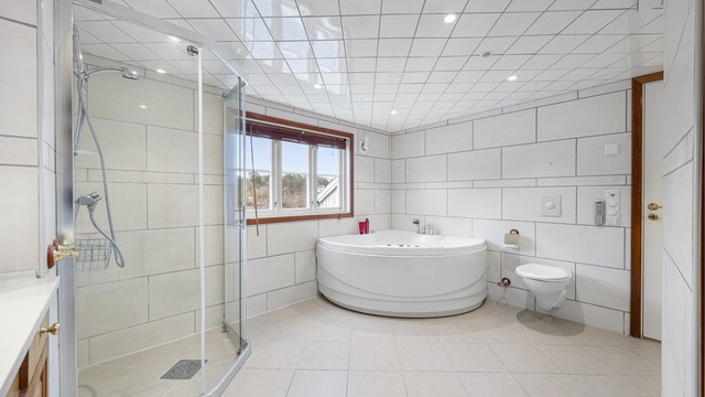 Stort bad med boblebad, varmekabler, stor dusj, servant, vegghengt toalett med mer.