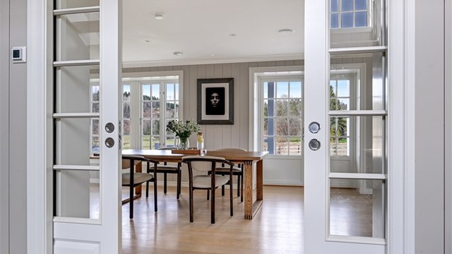De doble fyllingsdørene i tre med glassfelt skiller hallen fra spisestuen på en elegant måte.