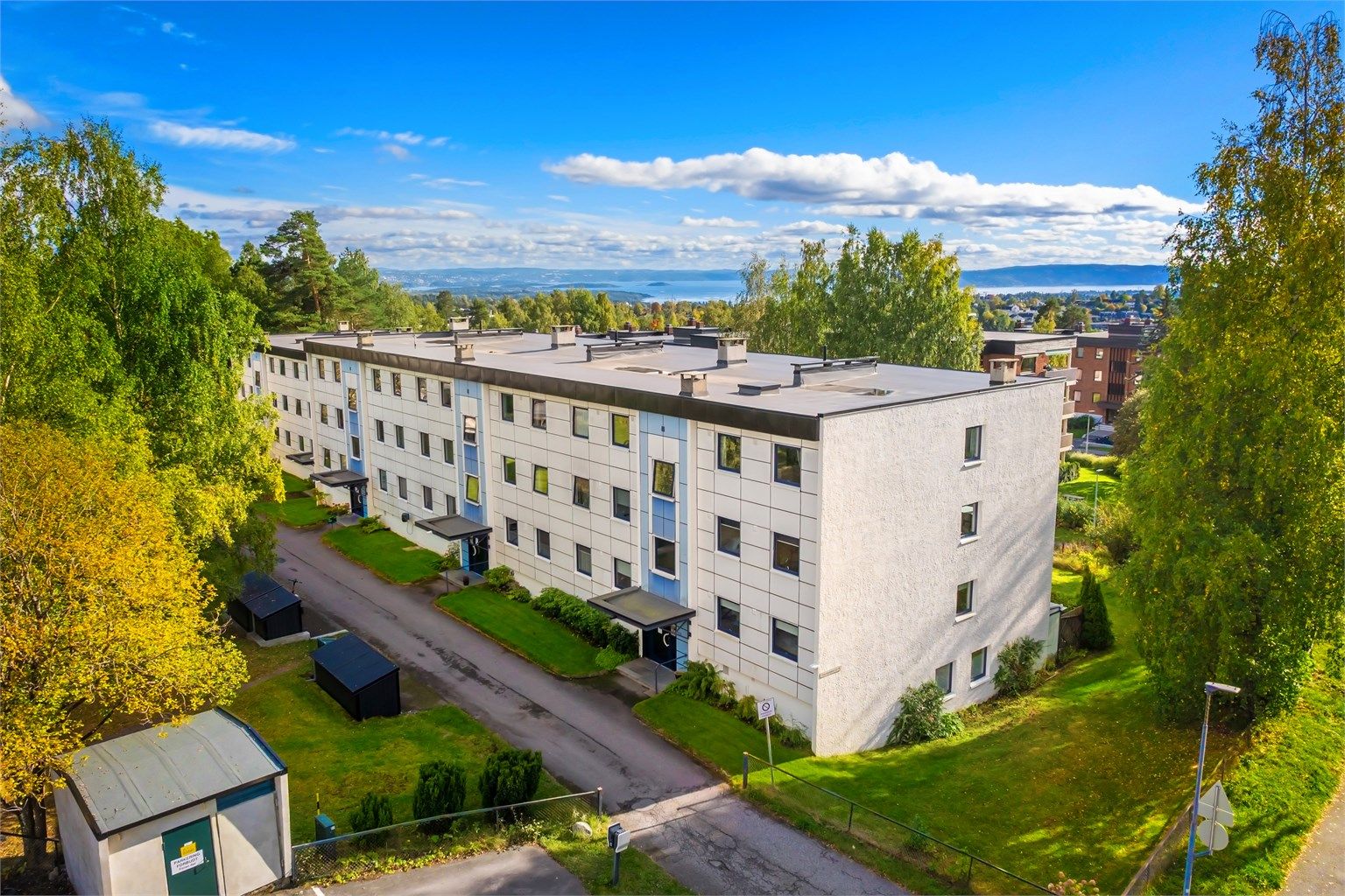 Blokken er omgitt av store, grønne fellesarealer med utsikt mot fjorden i det fjerne.