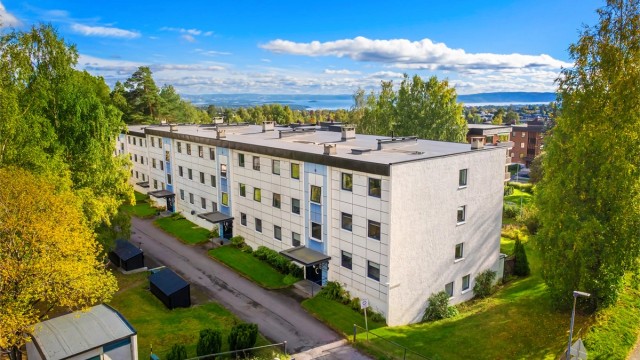 Blokken er omgitt av store, grønne fellesarealer med utsikt mot fjorden i det fjerne.