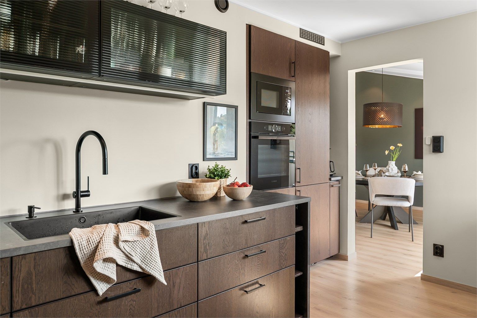 Moderne kjøkken fra 2024. Kjøkkenet har mørke fronter og detaljer som spiller godt med boligens ellers lyse fargevalg