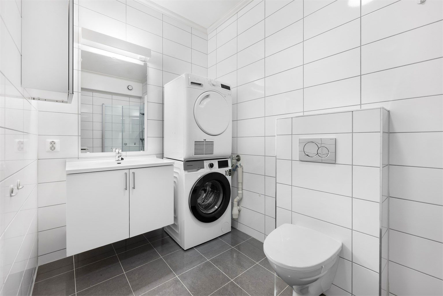 Kjellerleilighet - Badet er helfliset med gulvvarme og innredet med baderomsmøbler, vegghengt wc og dusjhjørne