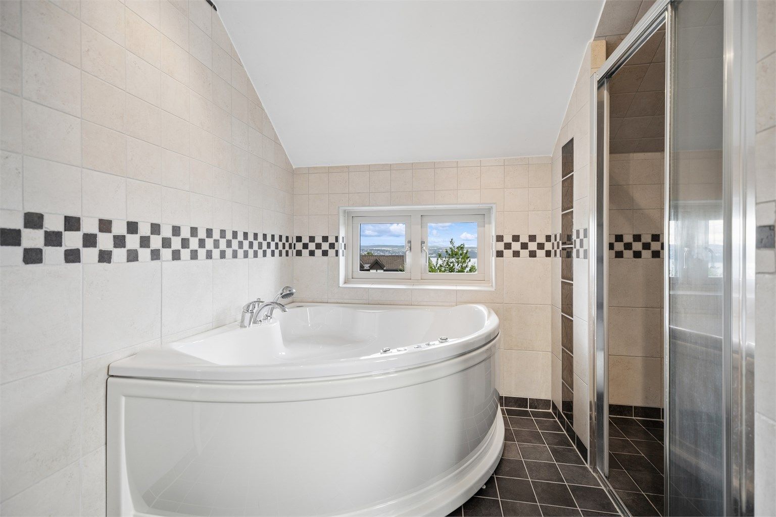Baderommet er romslig med hjørnebadekar/jacuzzi, dusjnisje og flott utsikt over fjorden. Et perfekt rom for avslapning og velvære.