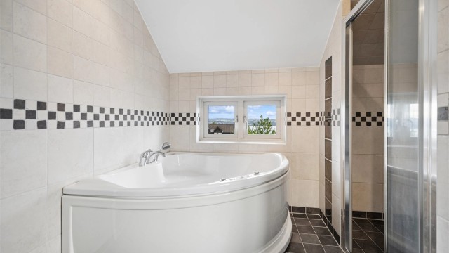 Baderommet er romslig med hjørnebadekar/jacuzzi, dusjnisje og flott utsikt over fjorden. Et perfekt rom for avslapning og velvære.