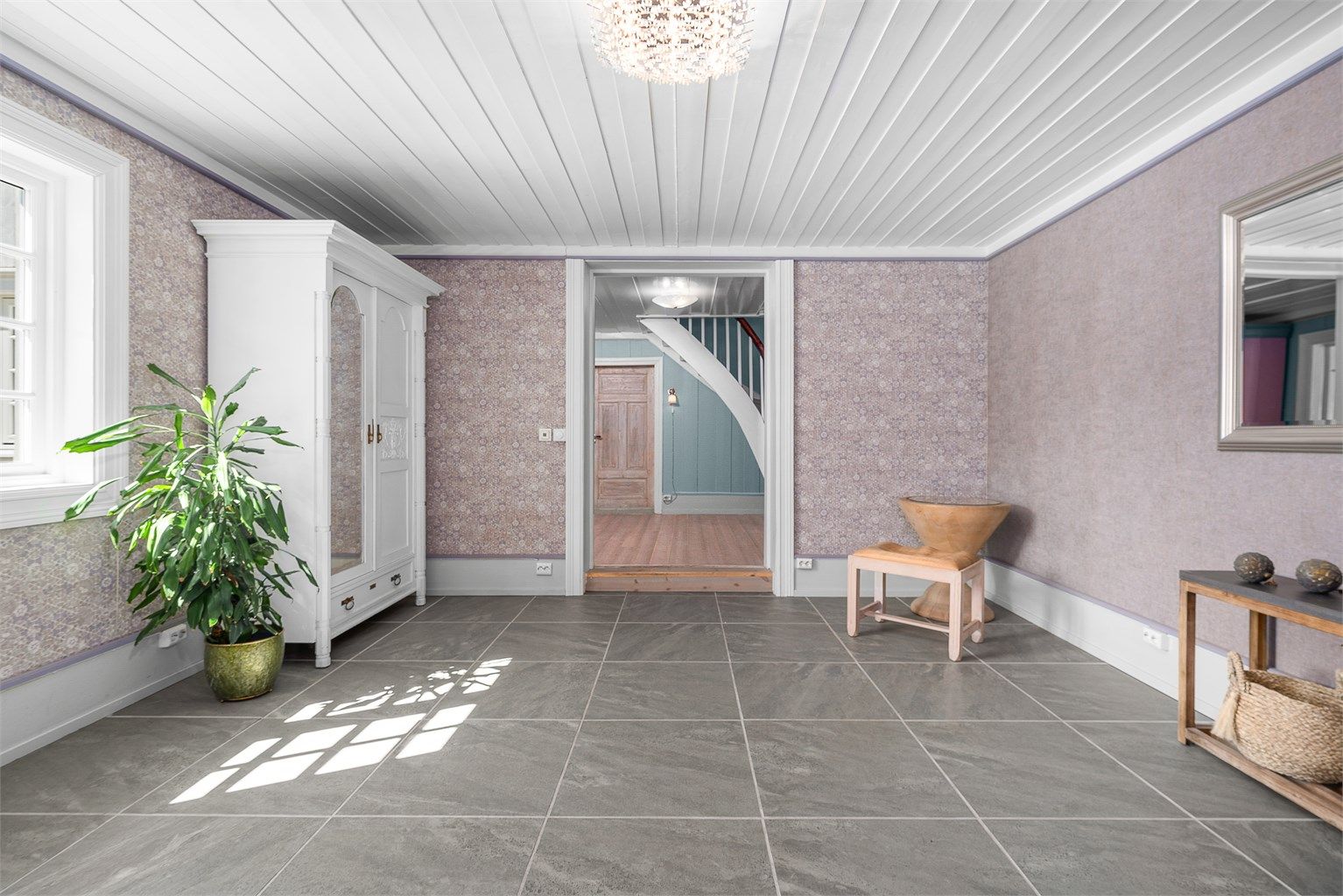Hallen er pusset opp i selgers eiertid, og har nå stilrene store fliser som passer godt inn i boligens estetikk